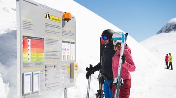 Skiers in front of Check your Risk board in the Ski Arlberg ski area