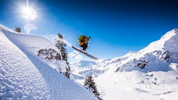 Freerider jumping over a rock in the Warth-Schröcken region